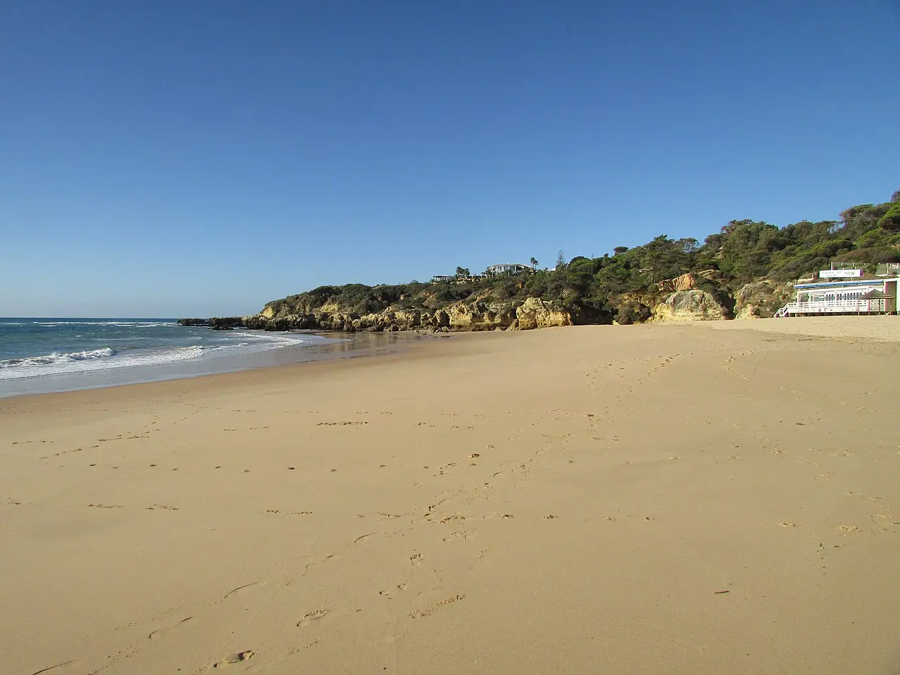 La arena y la orilla rocosa de la Praia da Oura