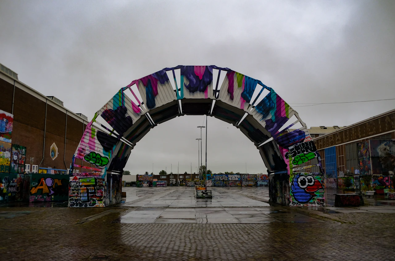 A graffiti-covered archway between industrial buildings at the NDSM shipyard