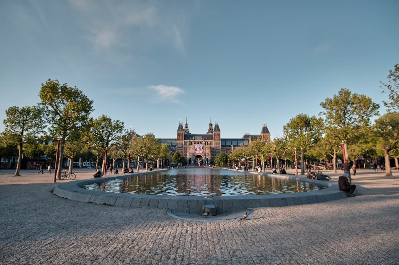 The Rijksmuseum beyond the reflecting pool and tree-lined paths of Museumplein