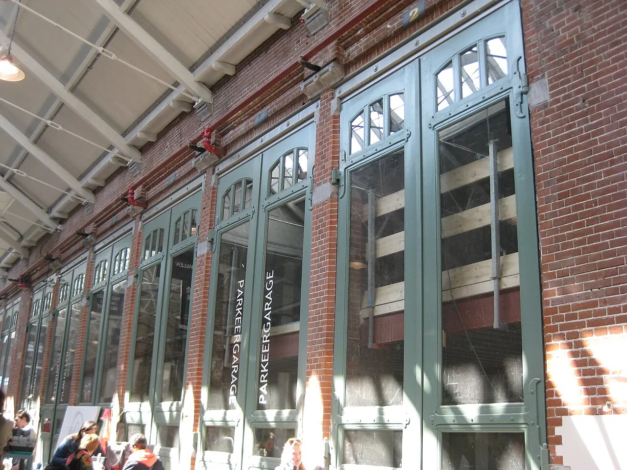 Brick walls and tall green former depot doors along the covered passage at De Hallen in Oud-West