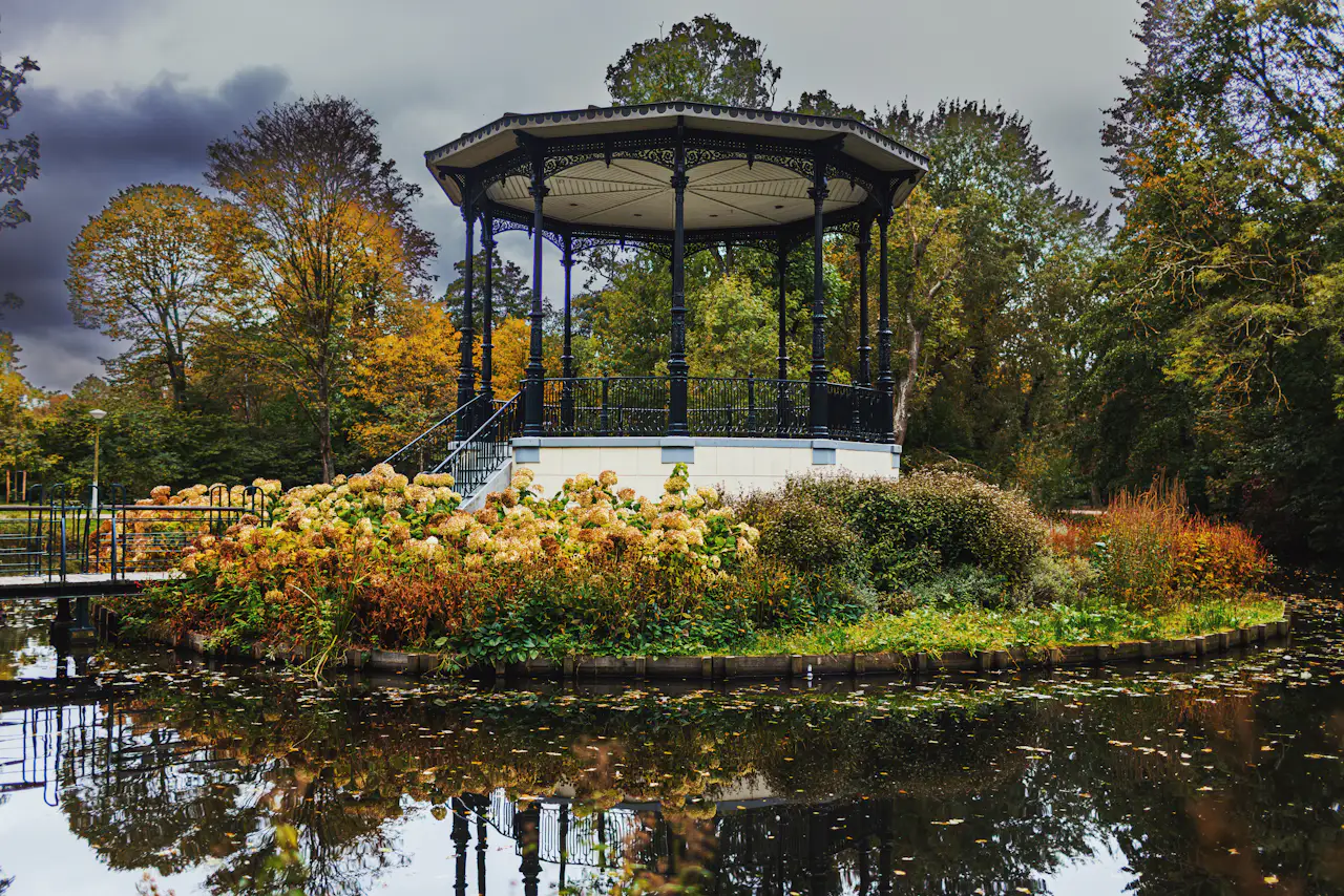 Vondelpark bandstand reflected in a pond, surrounded by hydrangeas and autumn trees