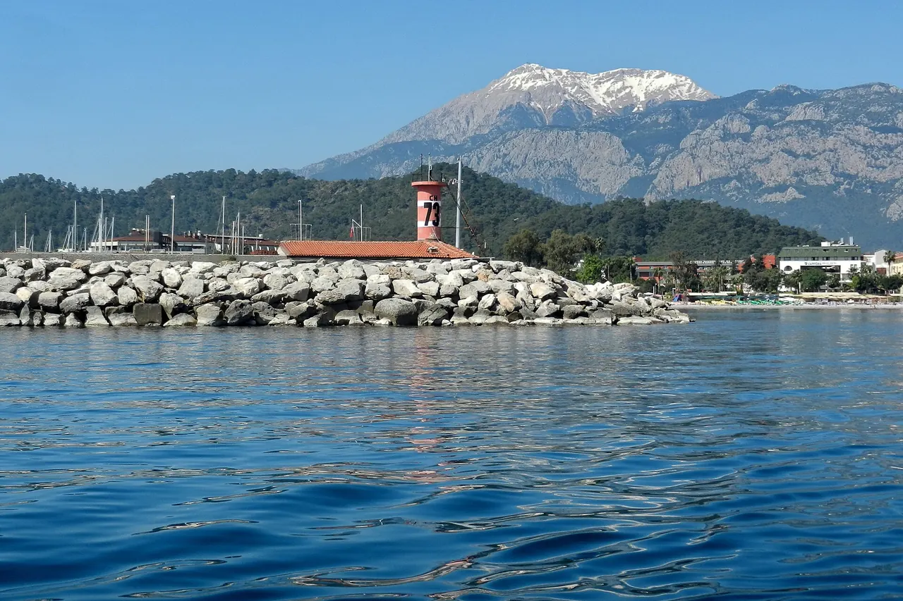 The breakwater and lighthouse at Kemer Marina with mountains behind