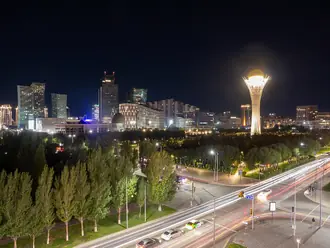 The illuminated Bayterek monument and surrounding Astana skyline at night
