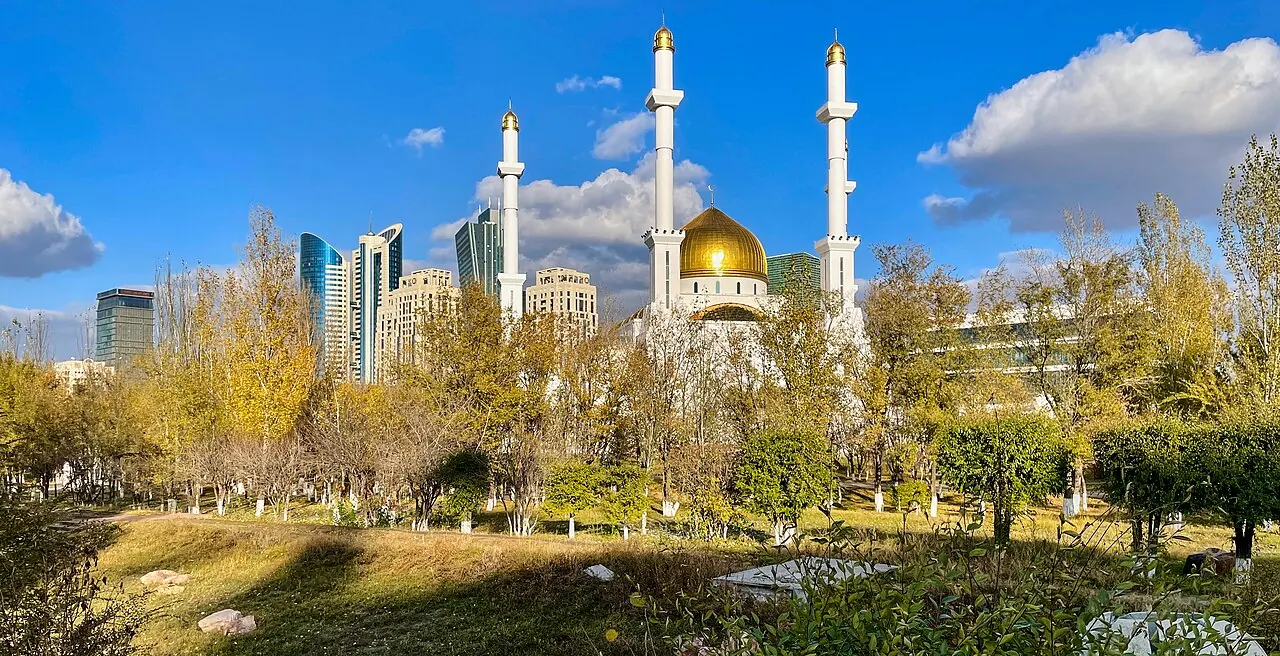 Golden domes and white minarets of Nur-Astana Mosque under a blue sky