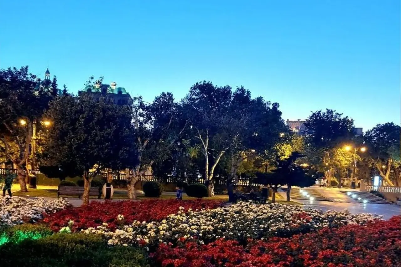 Flower beds, trees and illuminated paths in the gardens of Baku Boulevard
