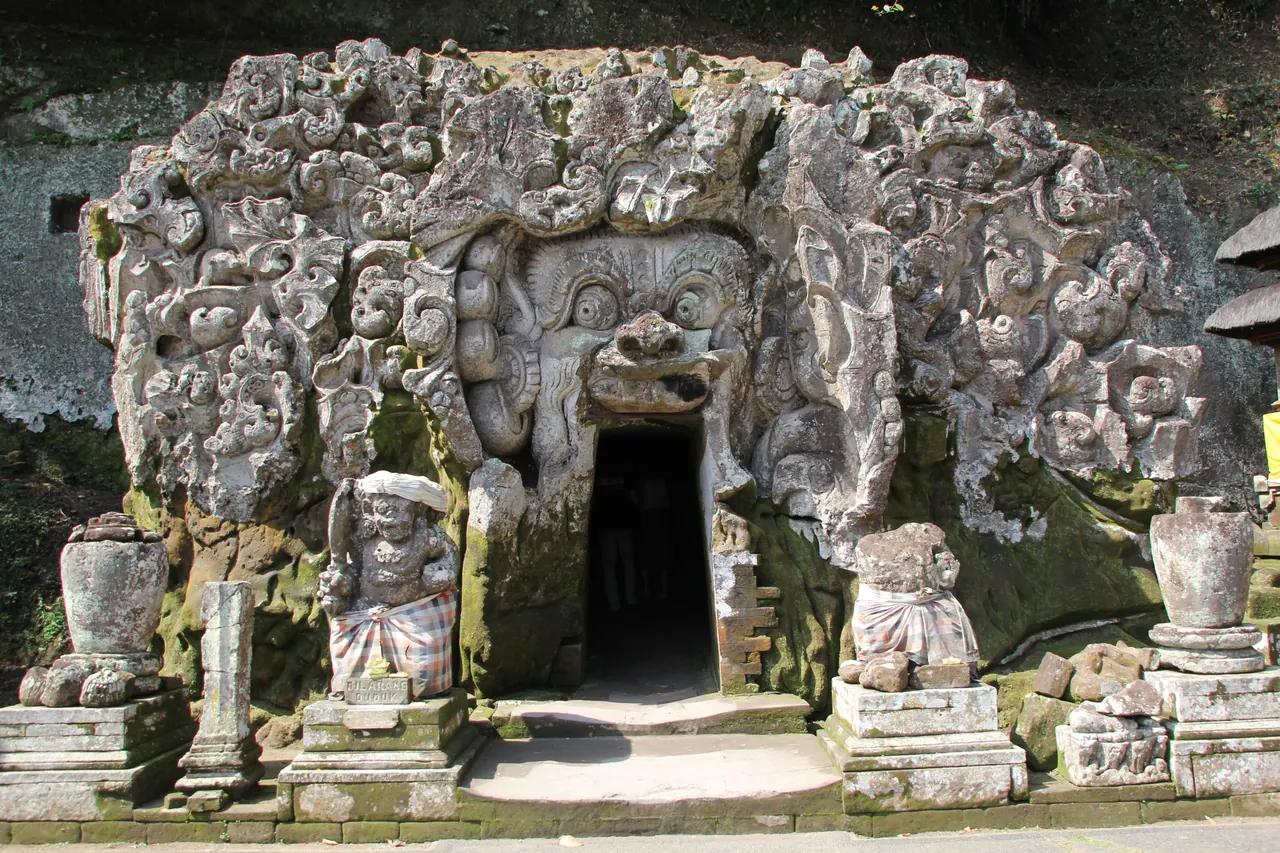 Carved stone face framing the cave entrance at Goa Gajah