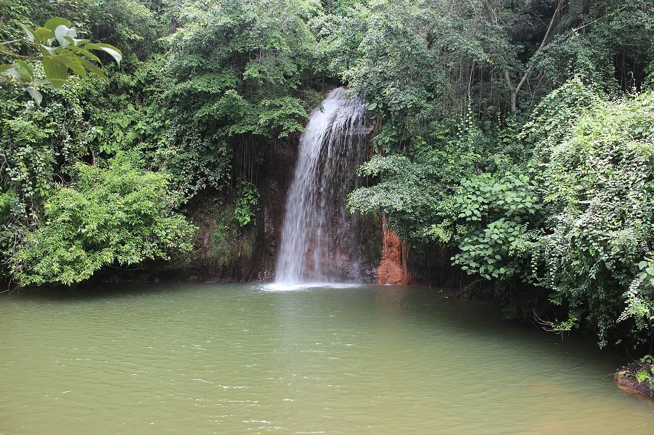 Tasek Lama's waterfall falling into a pool surrounded by tropical vegetation