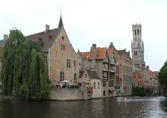 The Belfry of Bruges rising above the buildings beside the Dijver canal