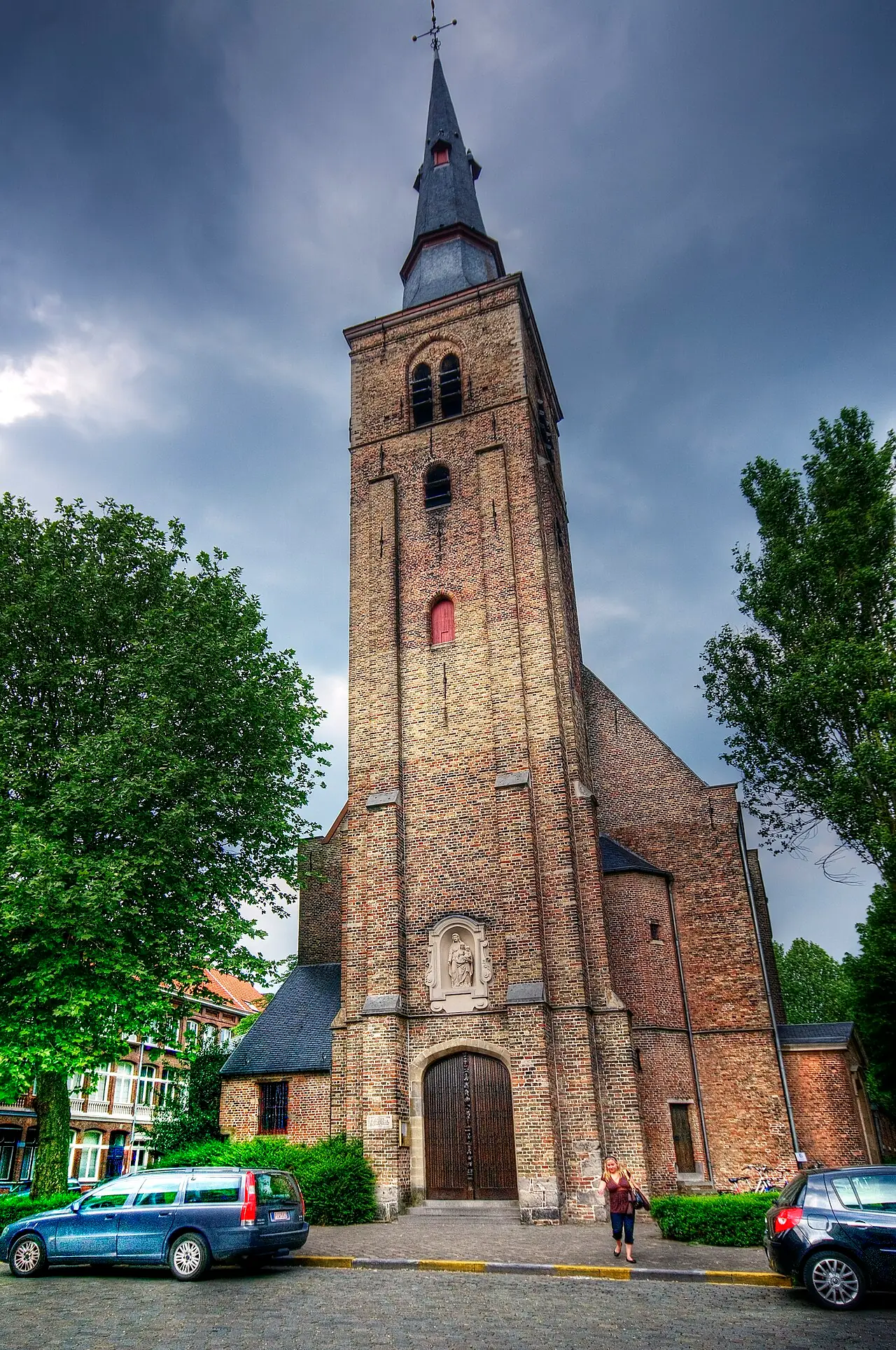The brick facade and tall spire of Sint-Annakerk on Sint-Annaplein in Bruges