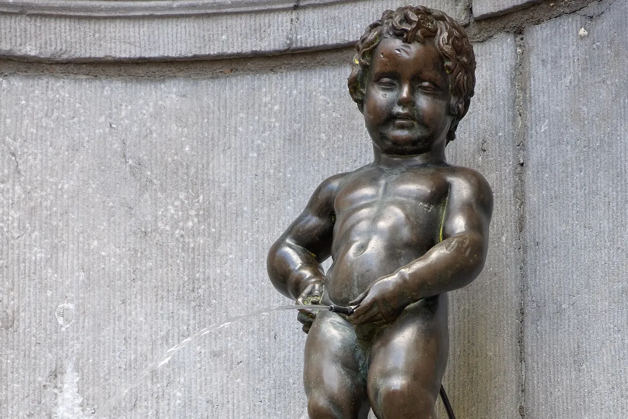 The small Manneken Pis fountain statue in its stone niche in Brussels