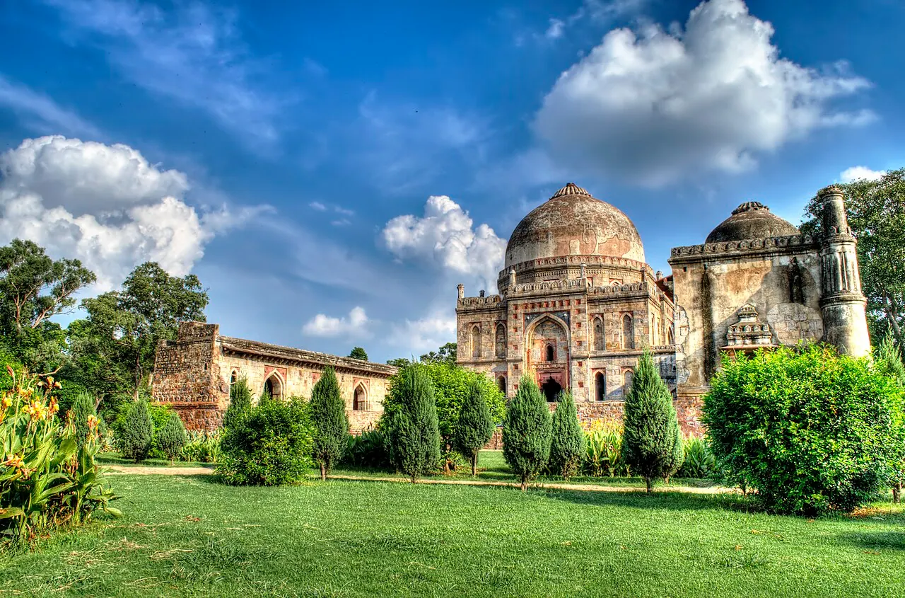 A domed historic monument and green lawns in Lodhi Gardens under a bright sky
