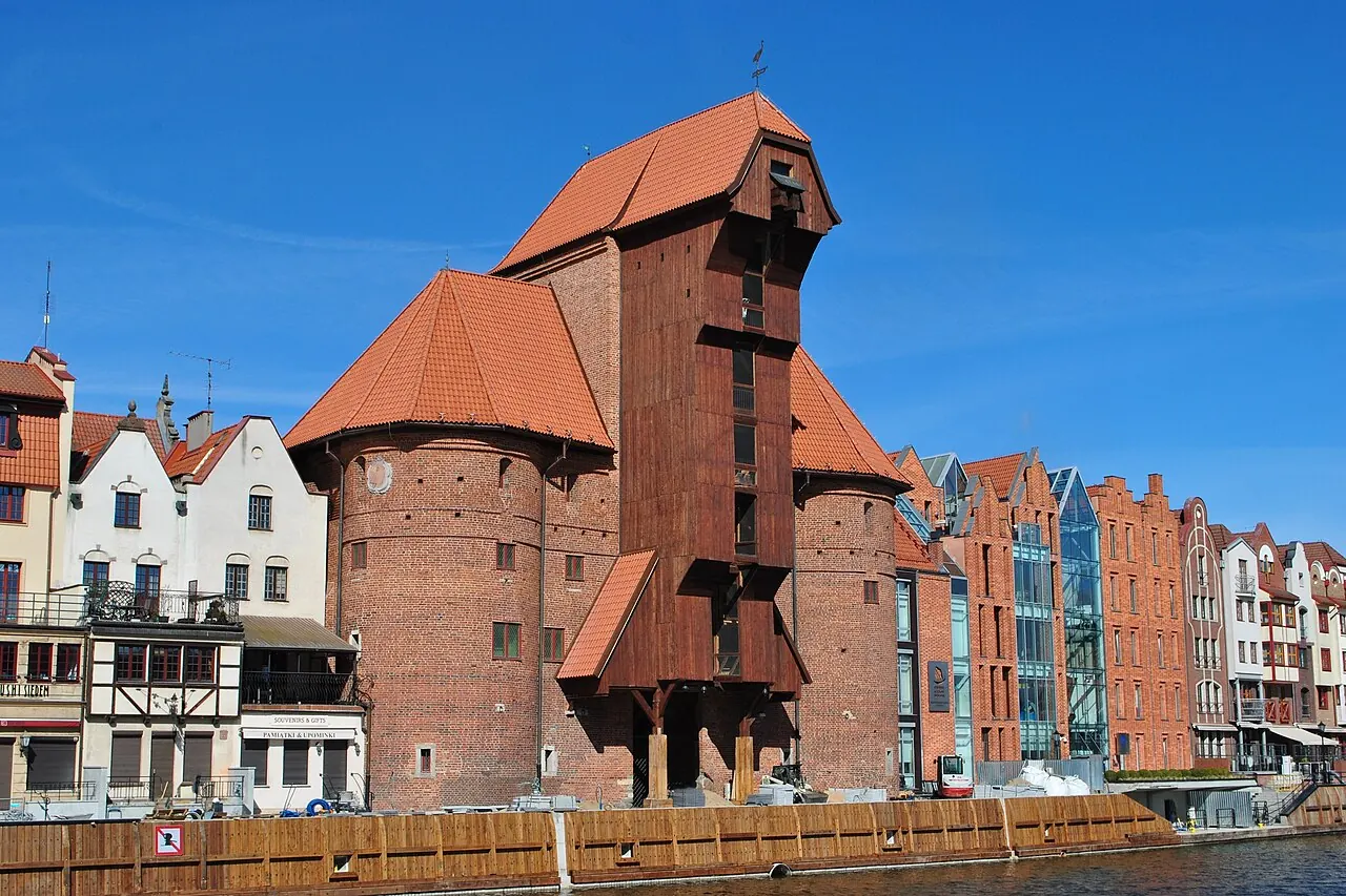 The wooden Gdansk Crane projecting between brick towers beside the Motlawa