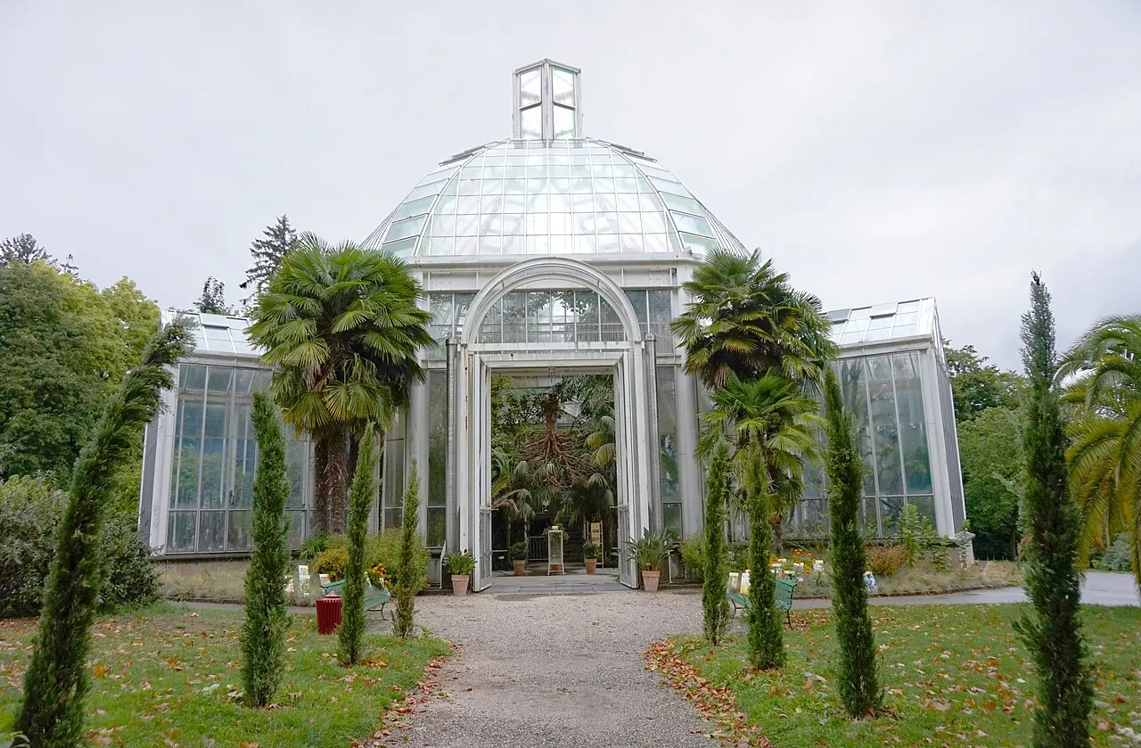 Glass conservatory surrounded by trees and lawns in Geneva’s botanical garden