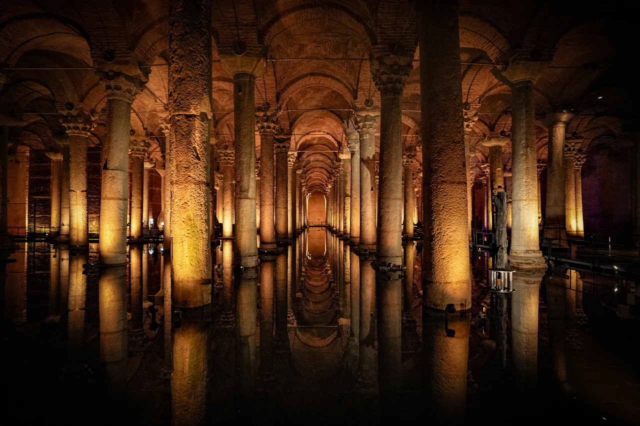 Verlichte stenen zuilen en gewelfde bogen weerspiegeld in het water van de Basilica Cisterne