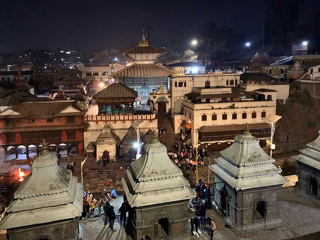 Pashupatinath's temple roofs and riverbank shrines illuminated at night
