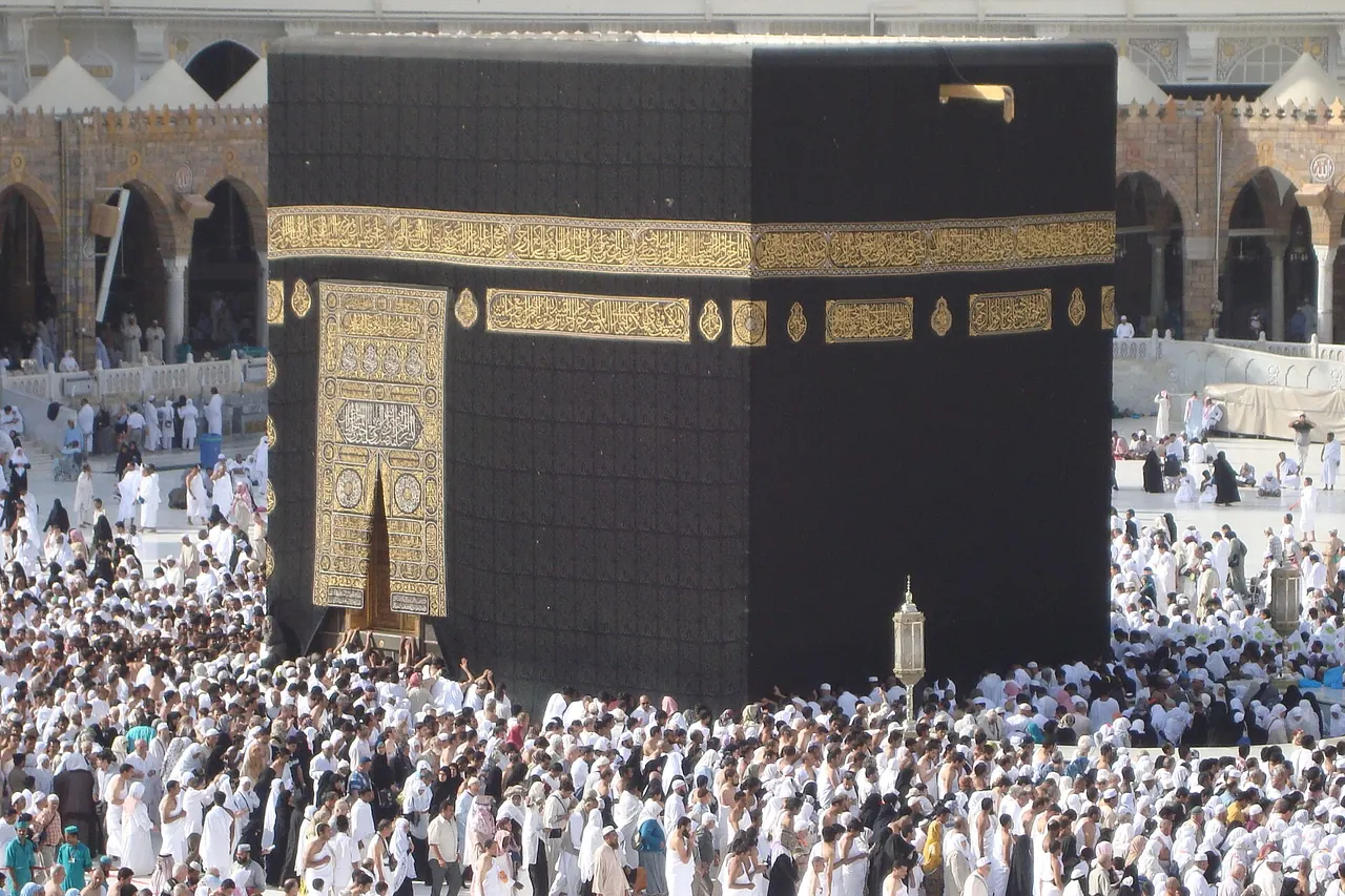 The black kiswah and gold decoration of the Kaaba above the surrounding crowd