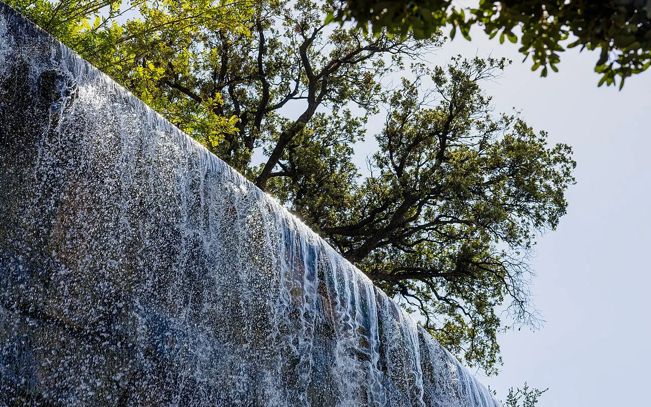 The artificial waterfall cascading below trees in Nice's Castle Hill park