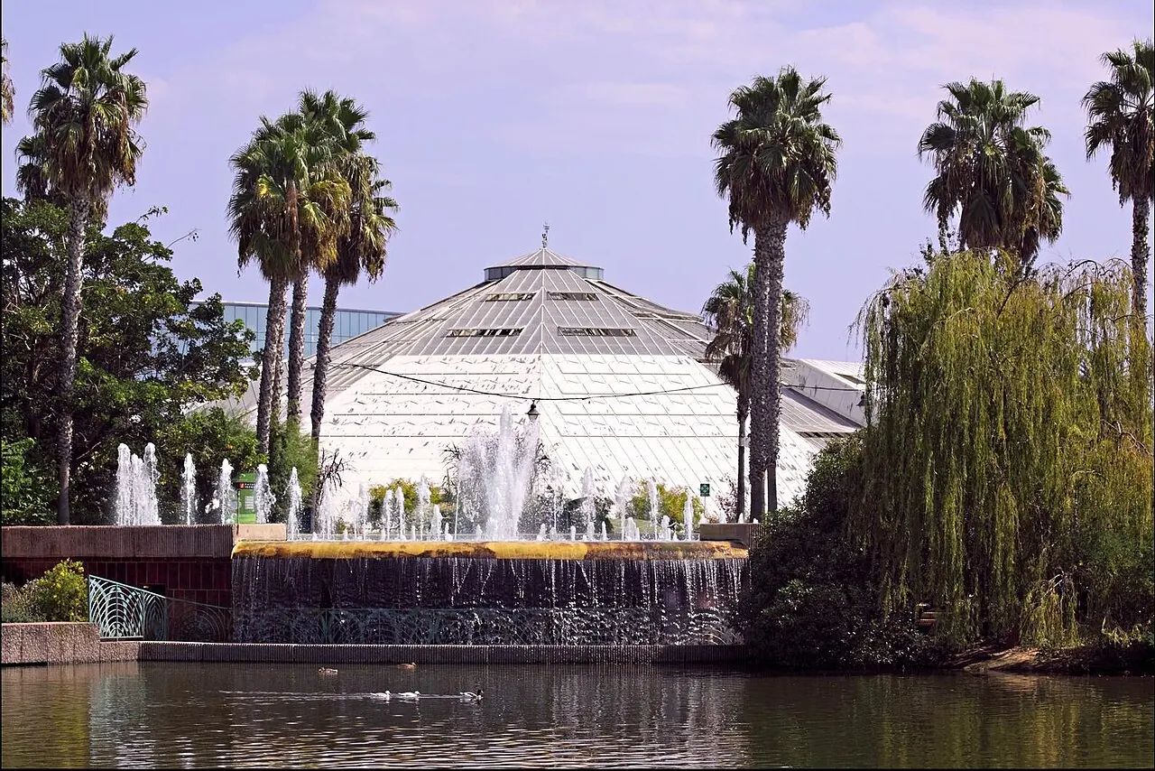 The large glasshouse of Parc Phoenix behind landscaped gardens and palm trees