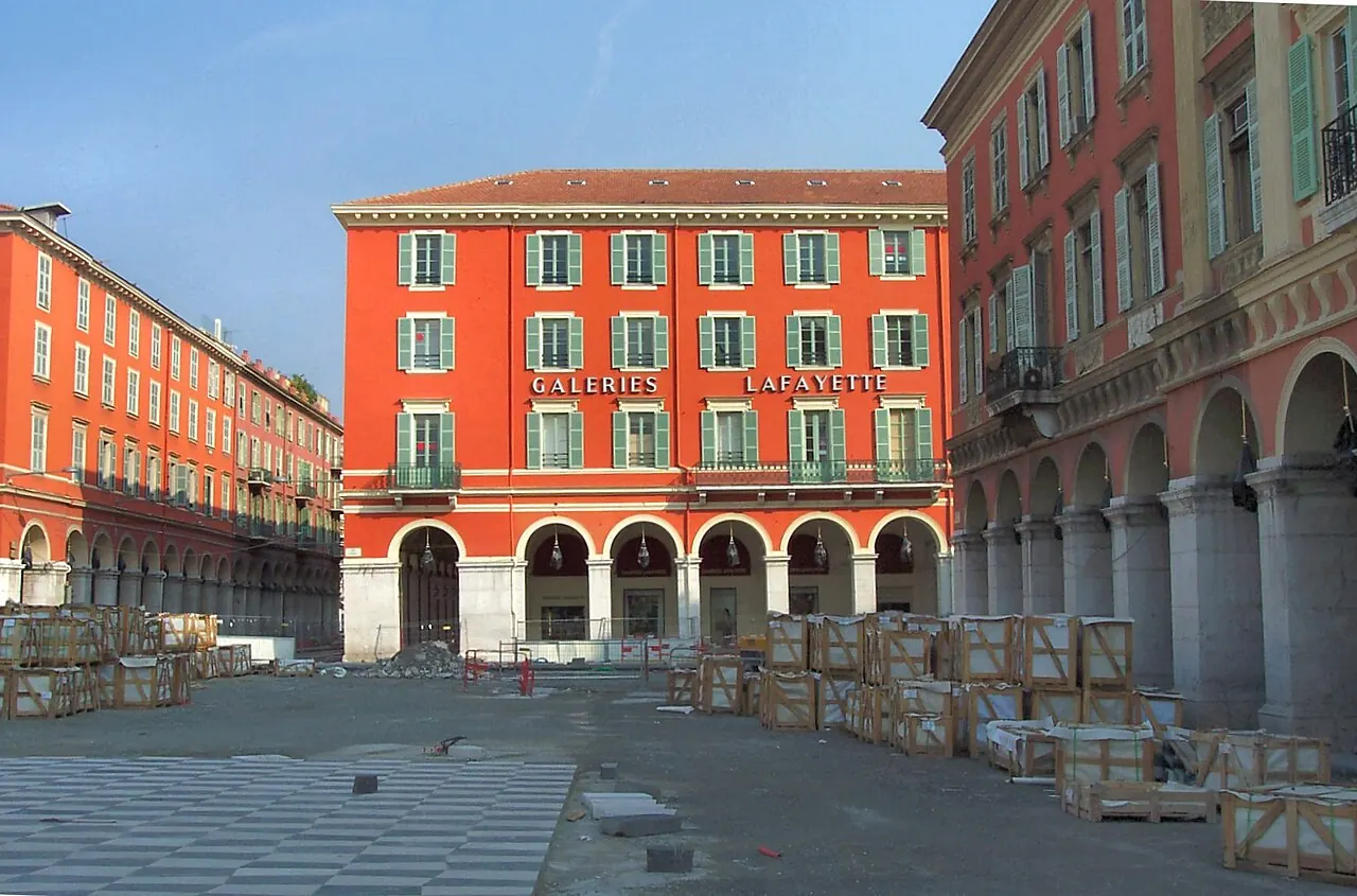 Red facades, arcades and patterned paving around Place Massena in Nice
