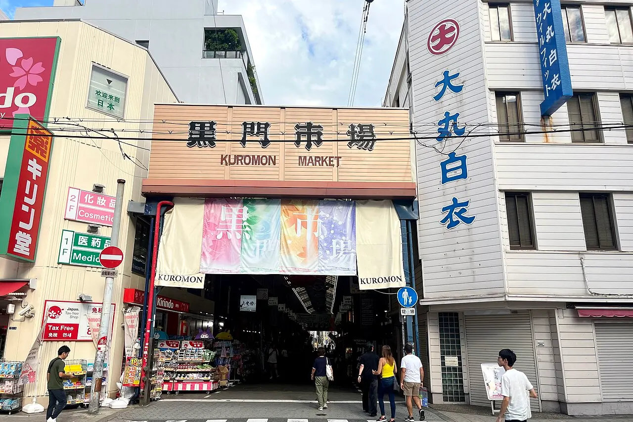 The covered Kuromon Market arcade lined with food shops and hanging signs