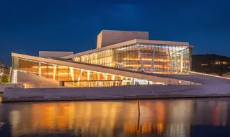 The white sloping roof and glass facade of Oslo Opera House beside the fjord