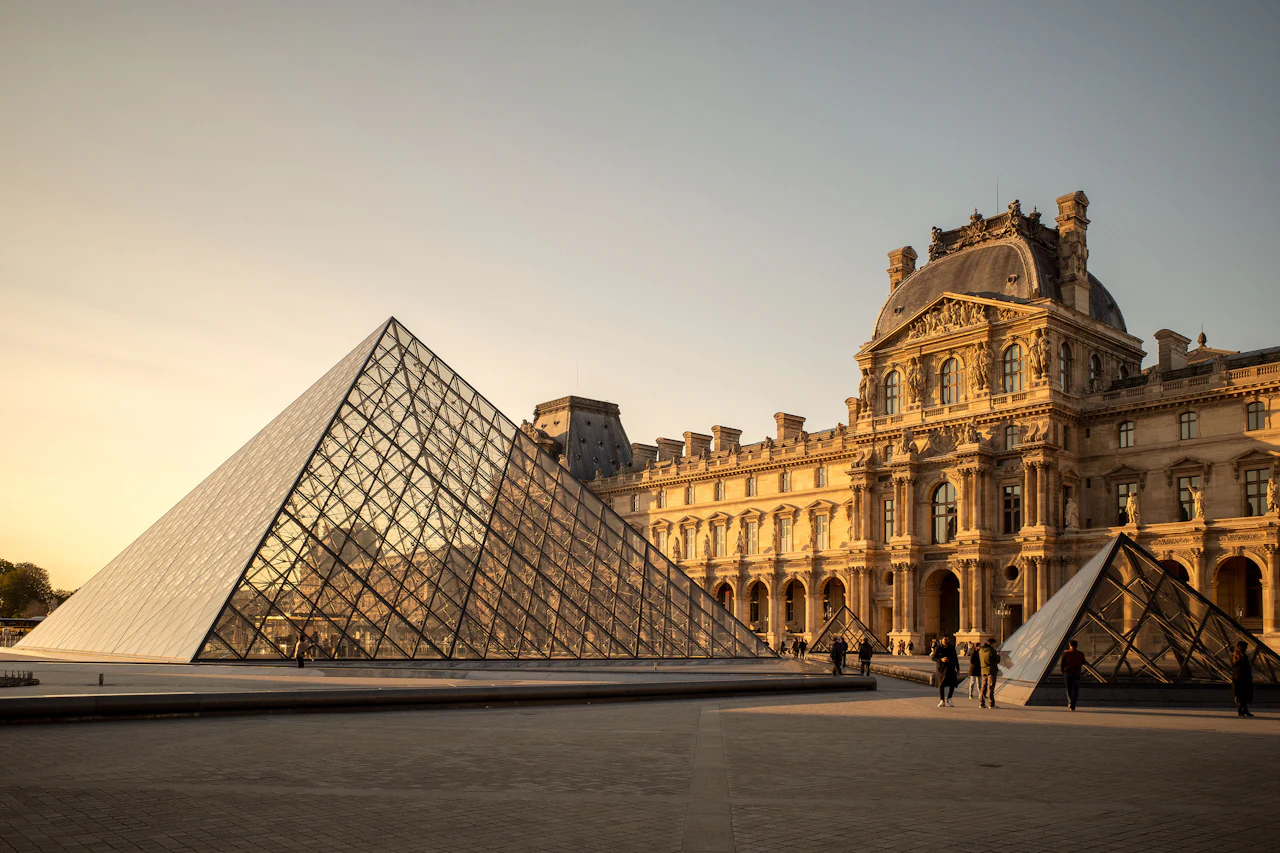 Glass pyramids and the Louvre palace courtyard in warm evening light