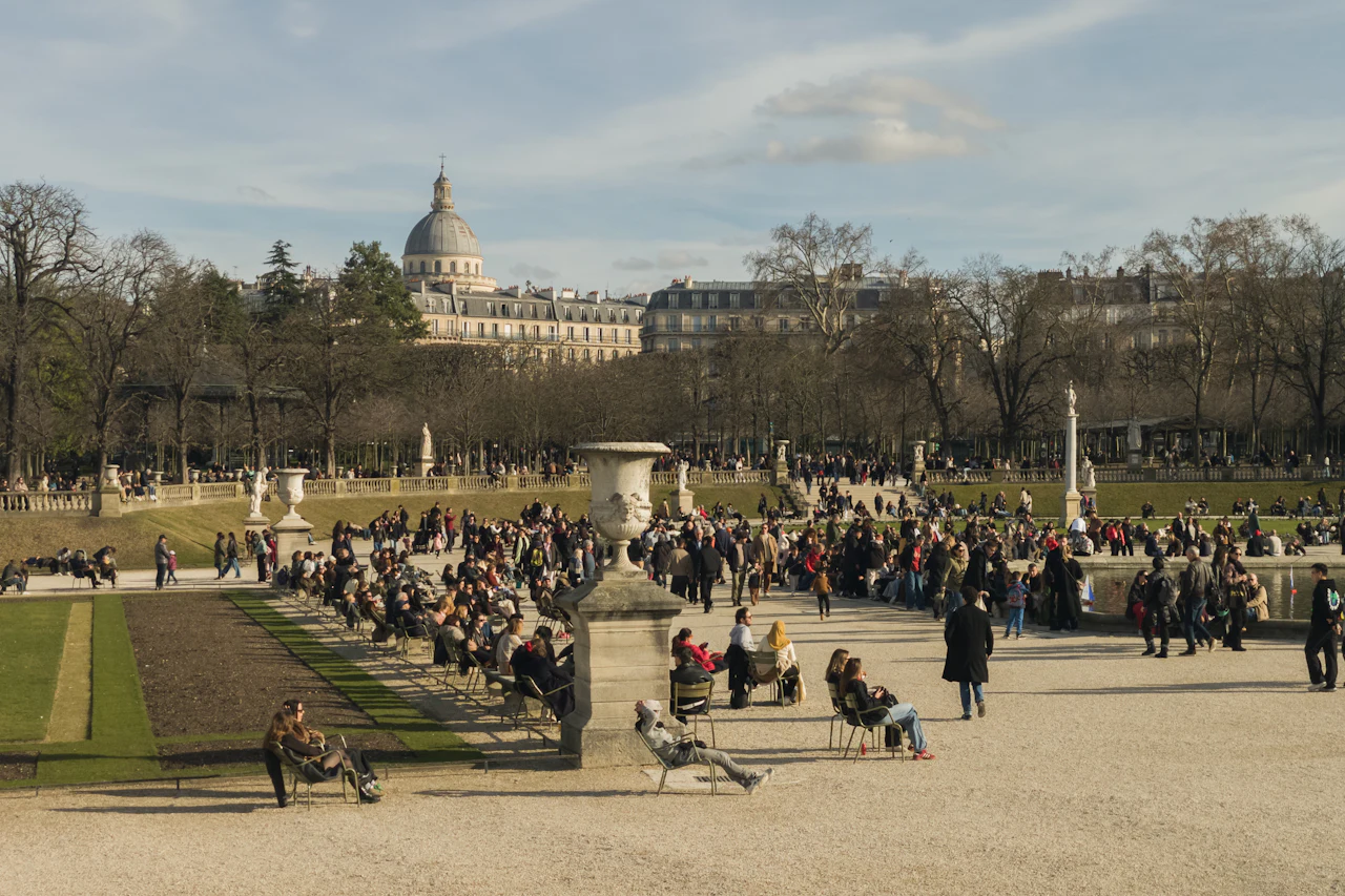 Visitors relaxing on chairs beside the lawns and paths of Luxembourg Garden