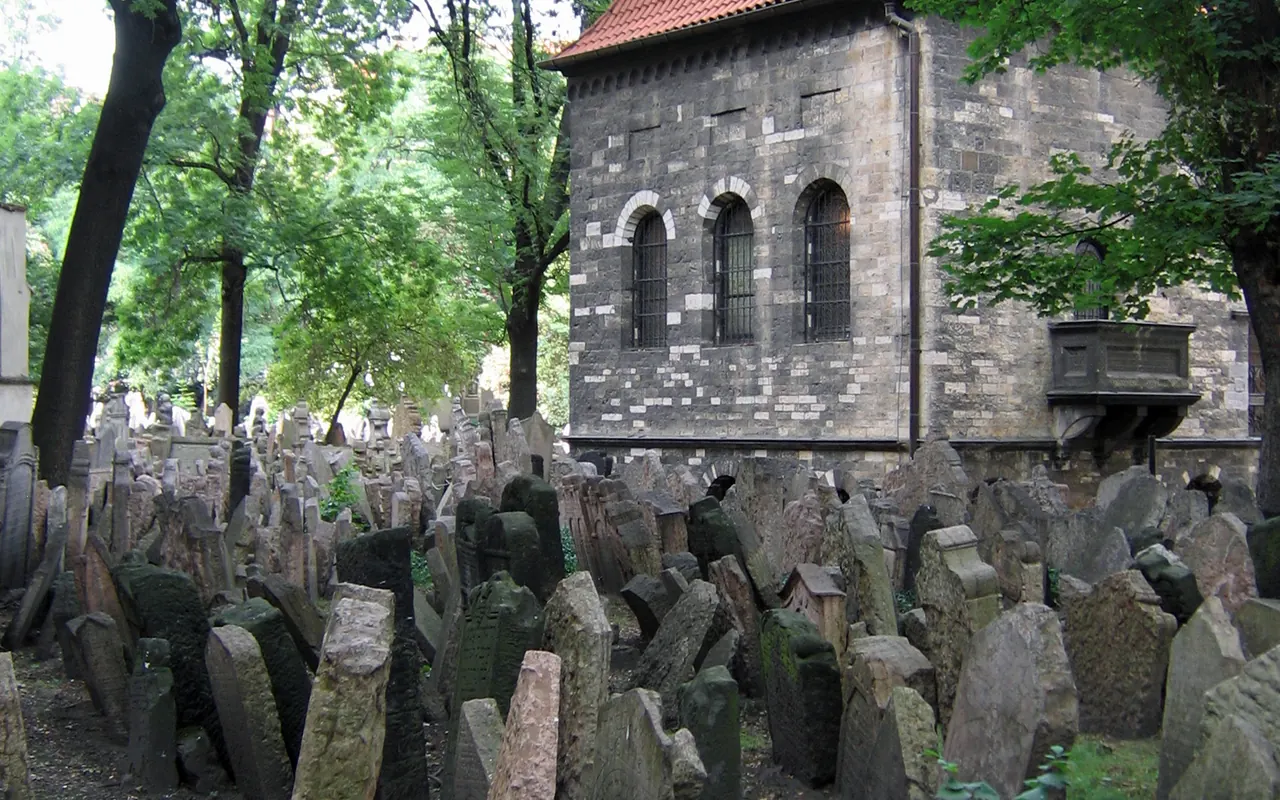 Closely spaced historic headstones beneath trees in Prague's Old Jewish Cemetery