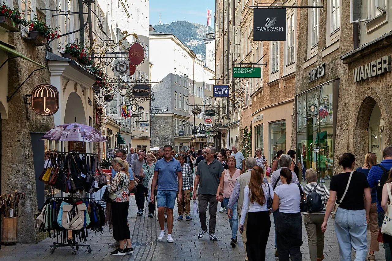 Pedestrians and ornate hanging signs along Getreidegasse in Salzburg