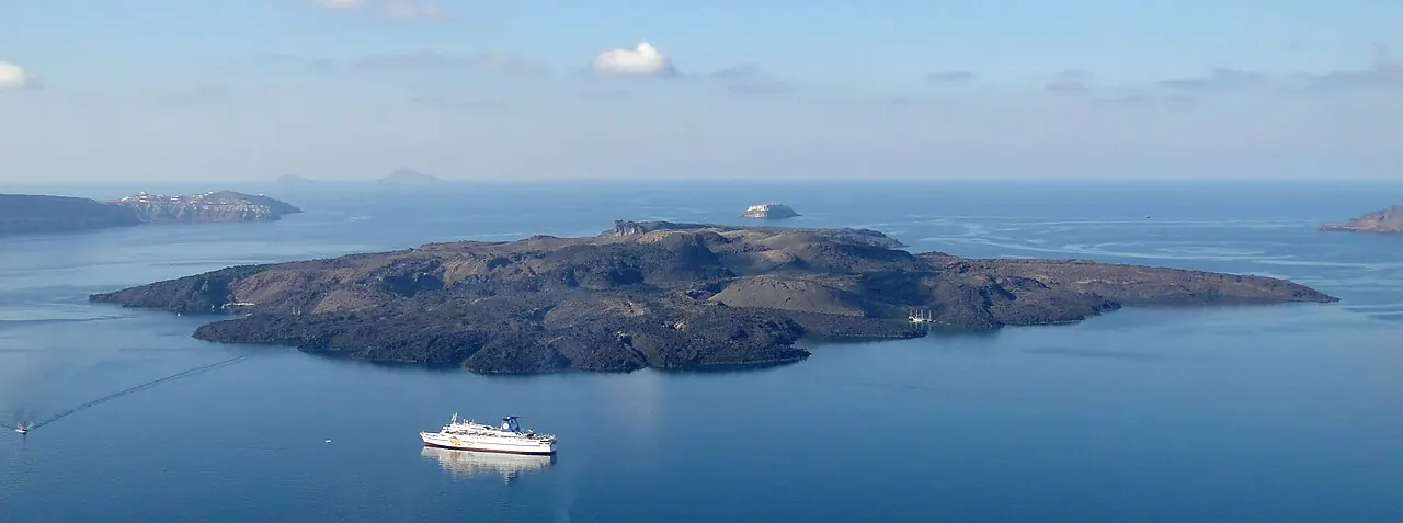 The dark volcanic island of Nea Kameni surrounded by the water of Santorini's caldera