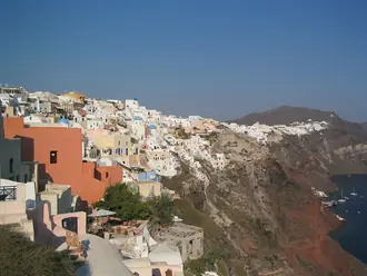 White buildings of Oia following the cliff above Santorini's caldera in daylight