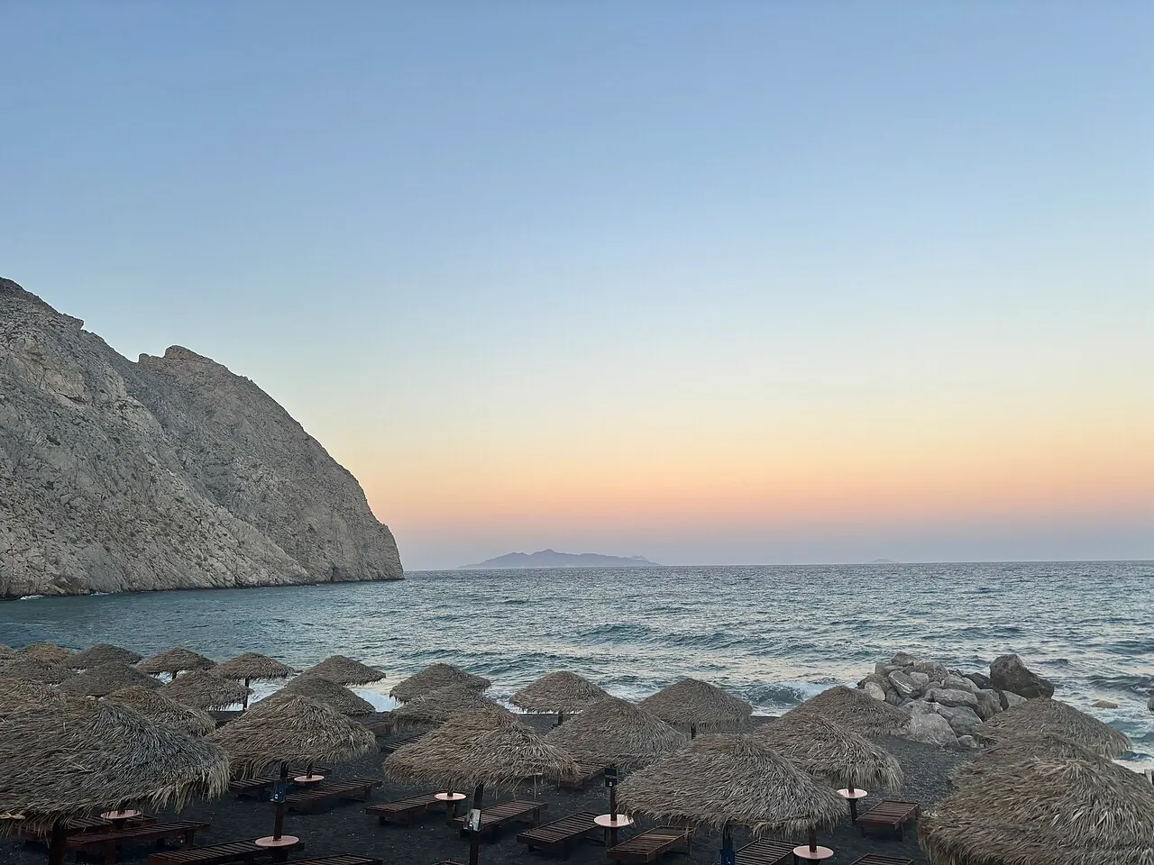 Perissa's dark beach at sunset with Mesa Vouno rising at the end of the shore