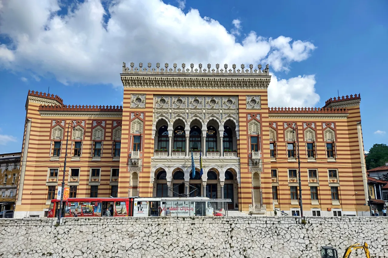 Gestreifte Fassade und Bogenfenster des Rathauses von Sarajevo an der Miljacka