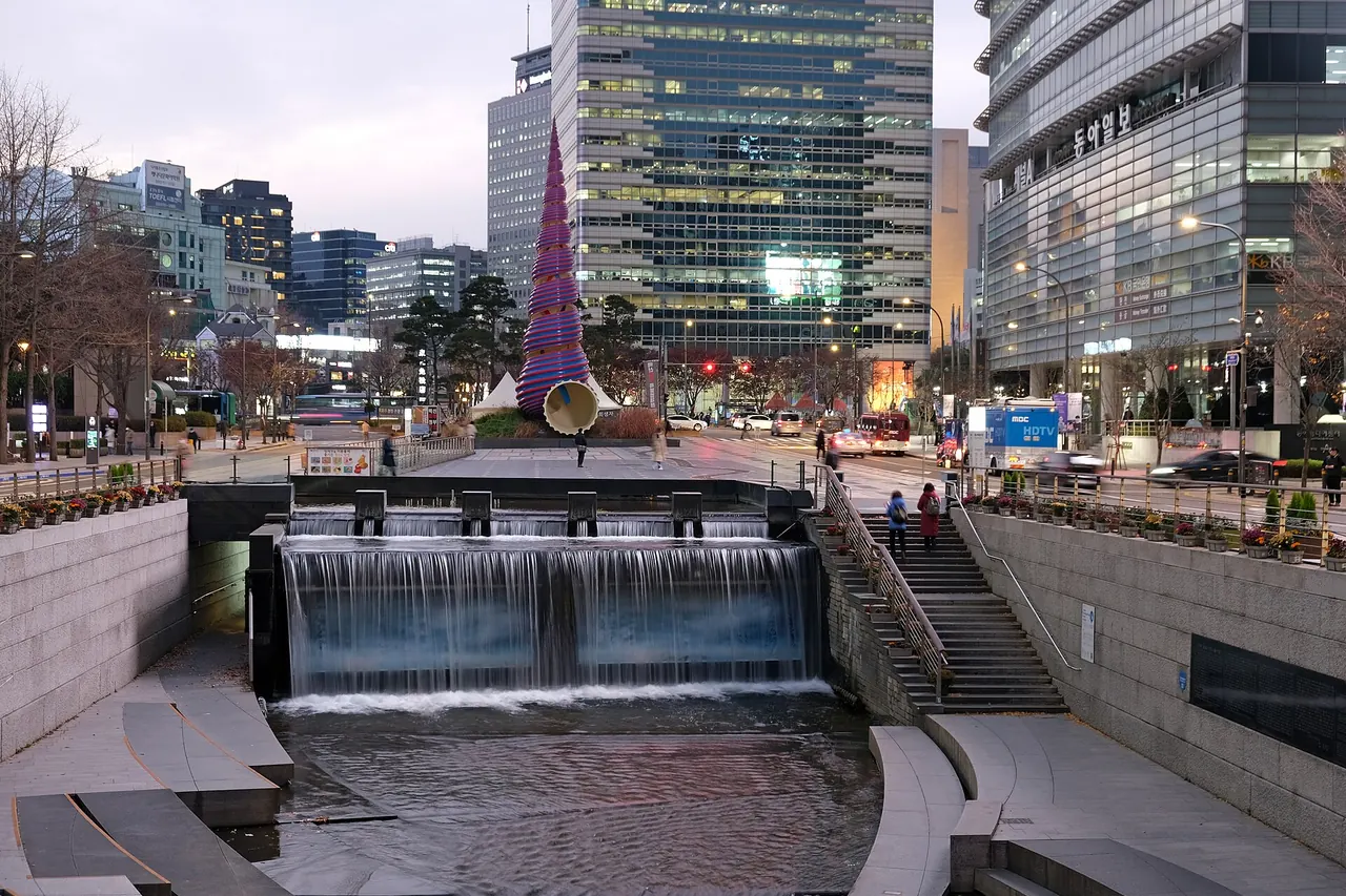 The lit stream channel and paths of Cheonggyecheon between city buildings