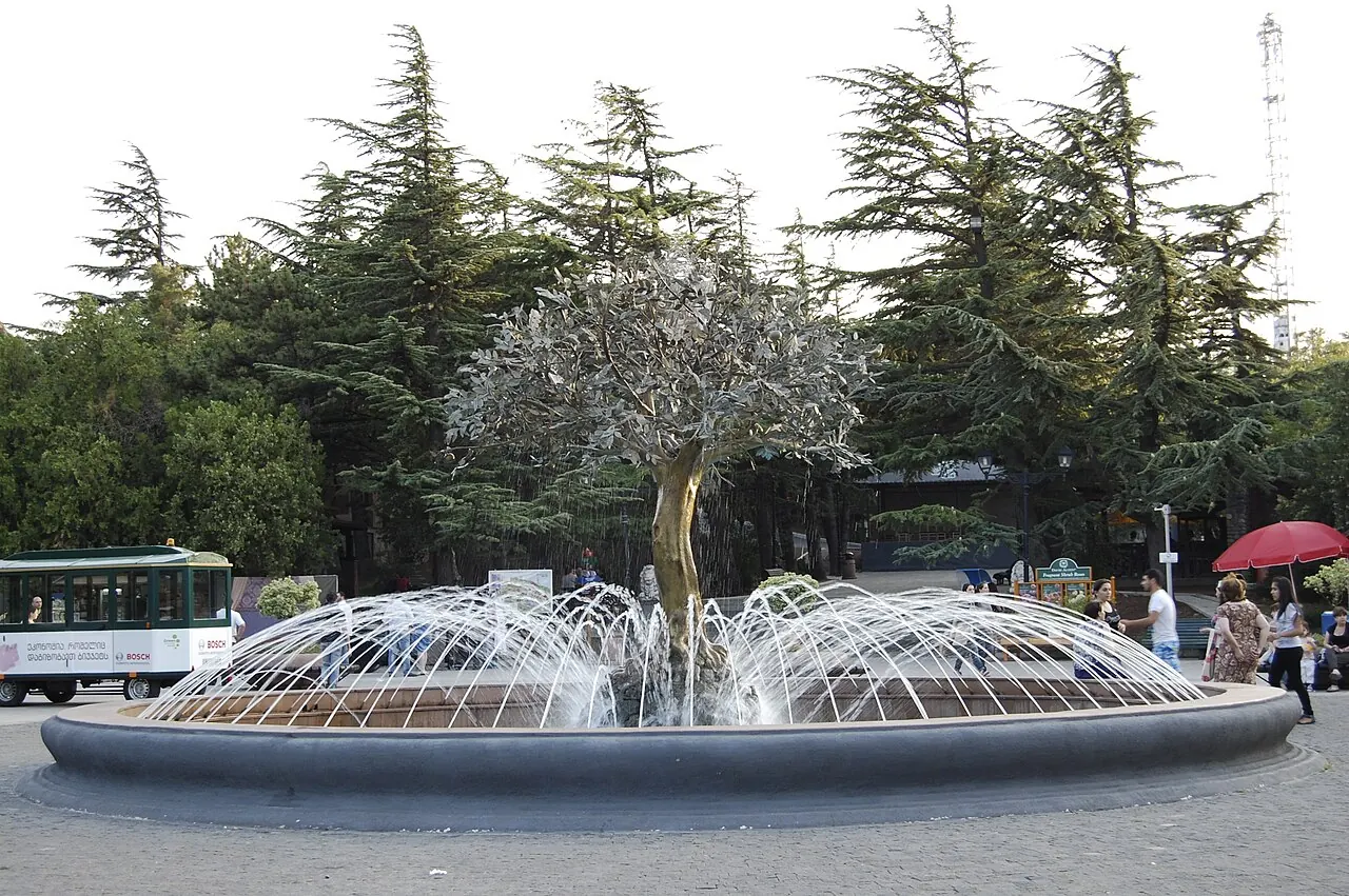 A fountain and park structures among trees at Mtatsminda Park