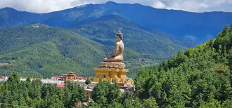 La statue dorée du Bouddha Dordenma au-dessus de collines boisées et de la vallée de Thimphou