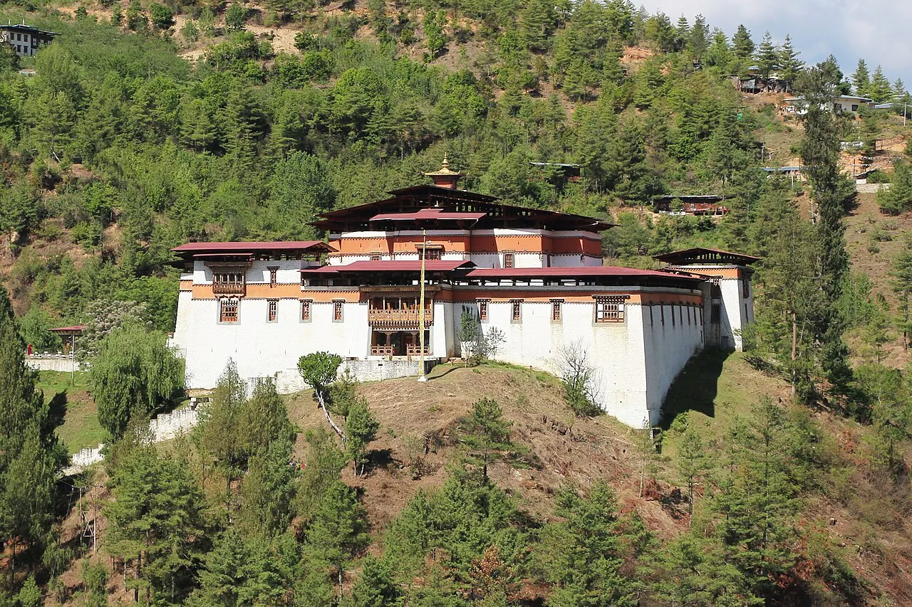 Weiße Festungsmauern und dunkle hölzerne Obergeschosse im Innenhof des Simtokha Dzong