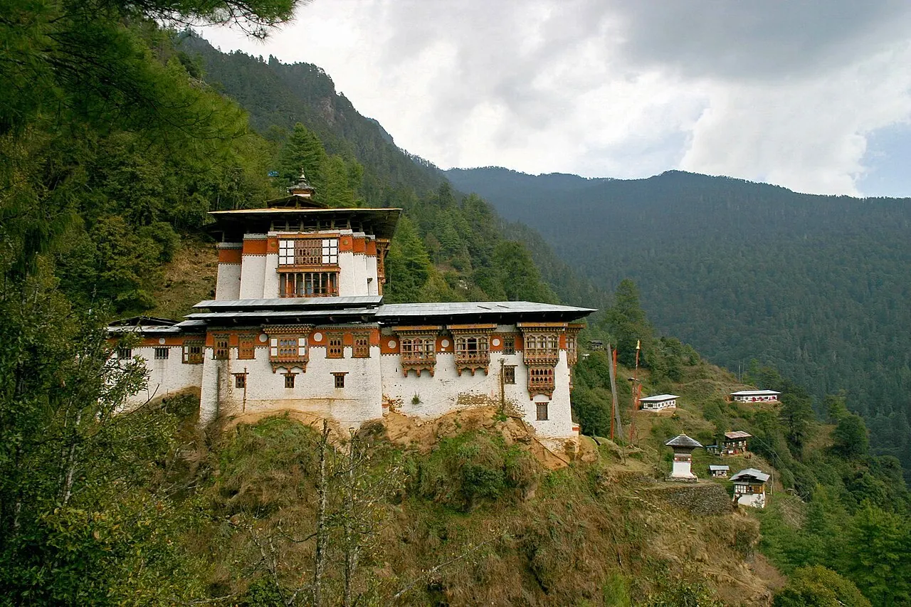 Die weißen Mauern und traditionellen Dächer des Klosters Tango an einem bewaldeten Berghang bei Thimphu