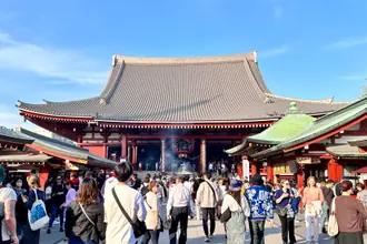 Le pavillon principal rouge du temple Senso-ji sous un ciel bleu à Tokyo