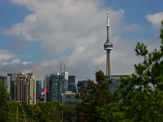 The CN Tower rising above Toronto buildings with a Canadian flag in the foreground
