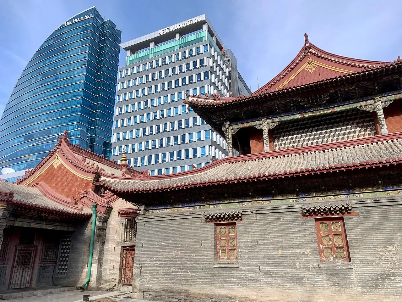 Ornately roofed buildings of Choijin Lama Temple Museum against modern Ulaanbaatar towers