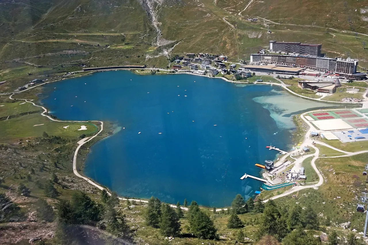 Der natürliche See von Tignes mit Gebäuden des Skiorts und Bergen