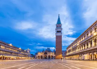 St. Mark's Square, its bell tower and illuminated arcades in Venice at dusk