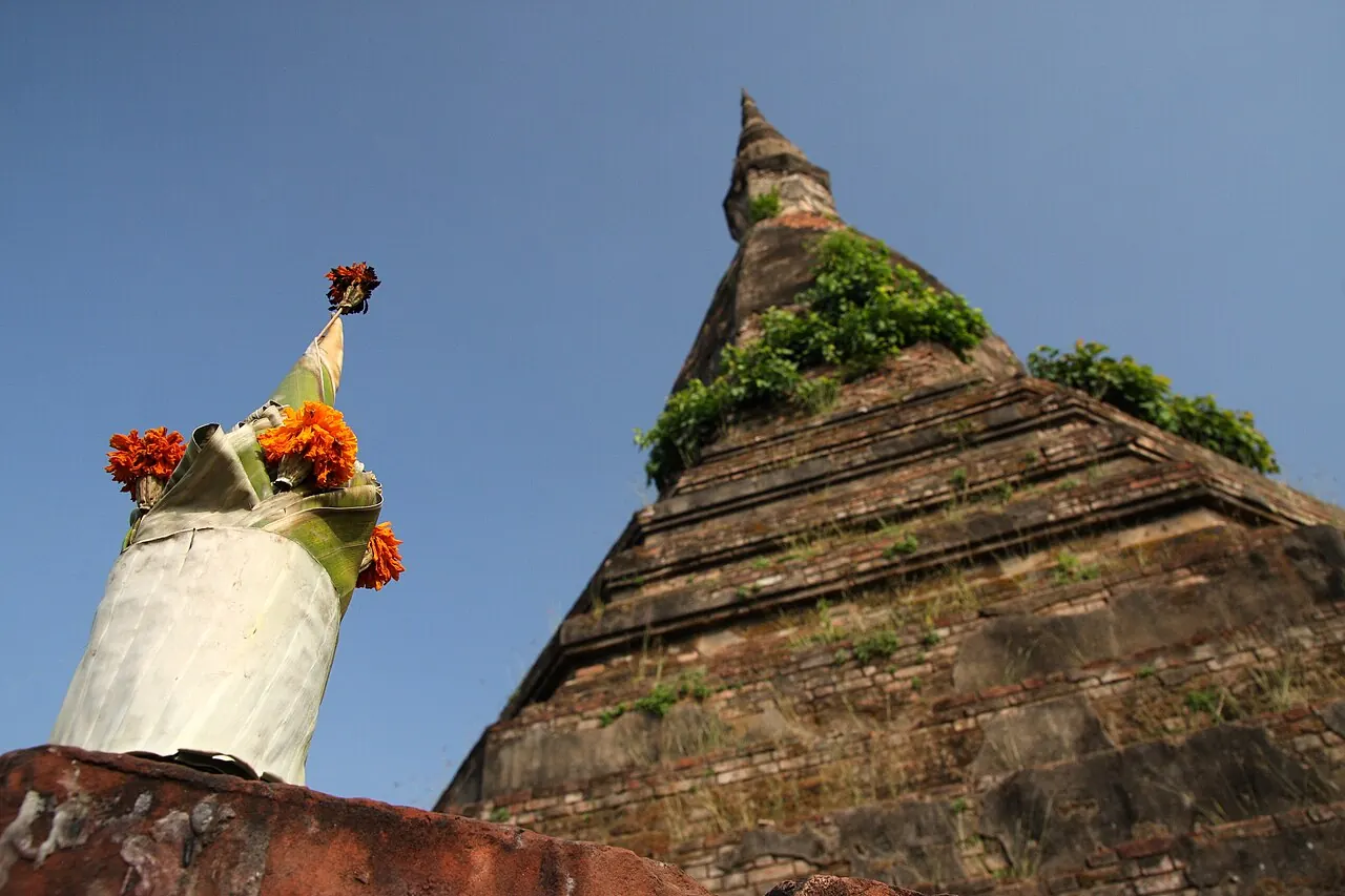 That Dam's weathered stupa beside a small shrine and offerings